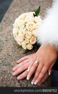 hands of new married with golden rings and bouquet