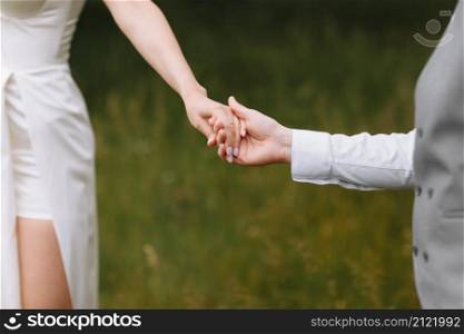 Hands of newlyweds close-up. The groom holds the bride&rsquo;s hands. loving couple holding hands while walking outdoors. Hands of newlyweds close-up. The groom holds the bride&rsquo;s hands. loving couple holding hands while walking outdoors.