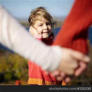 hands of parents and smiling daughter, focus point on face