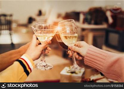 Hands of people celebrating New year party in home with wine drinking glasses and present background. New year and Christmas party concept. Happiness and Friendship and Funny together. Clinking glass