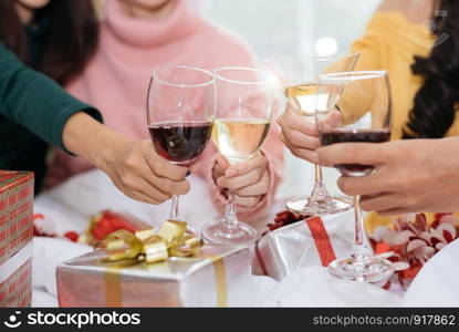 Hands of people celebrating New year party in home with wine drinking glasses and present background. New year and Christmas party concept. Happiness and Friendship and Funny together. Clinking glass