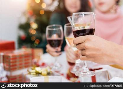 Hands of people celebrating New year party in home with wine drinking glasses and present background. New year and Christmas party concept. Happiness and Friendship and Funny together. Clinking glass
