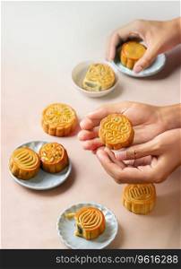 Hands of people eating tasty round moon cakes at mid autumn festival copy space