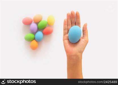 Hands of people holding colorful easter eggs on white background. Food decoration on holiday.