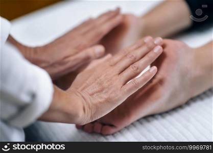 Hands of Reiki therapist healing and balancing feet chakras. Energy healing concept