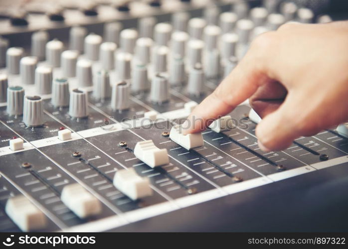 Hands of sound engineer working on recording studio mixer. Expert adjusting the volume of a voice, mixing console with mixer board.