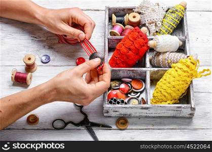 hands of tailor sewing accessories on background thread and buttons. Tools of seamstress for needlework