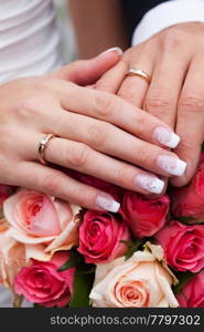 hands of the bride and groom with the rings lying on the bouquet