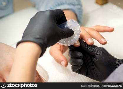 Hands of the manicure master removing dust from nails with a brush cleaning nails in nail salon. Hands of the manicure master removing dust from nails with a brush cleaning nails in nail salon.