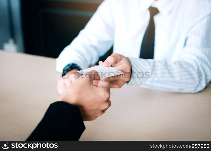 Hands of two business people sitting in office room giving and taking empty business card.