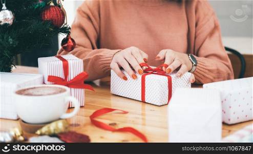 Hands of woman decorating Christmas and New Year gift box. Holiday concept.
