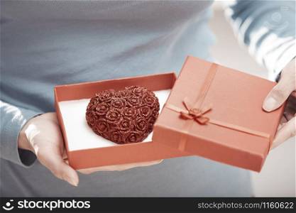 Hands of woman opening gift box with heart