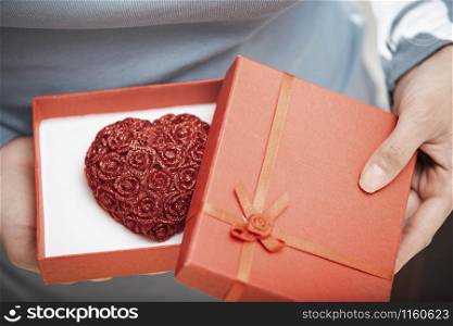 Hands of woman opening gift box with heart