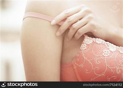 Hands of woman undressing pink bra