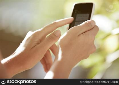 Hands of woman with smartphone in the garden
