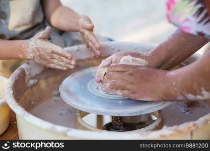 Hands of young potter, creating an earthen jar on the circle, close-up