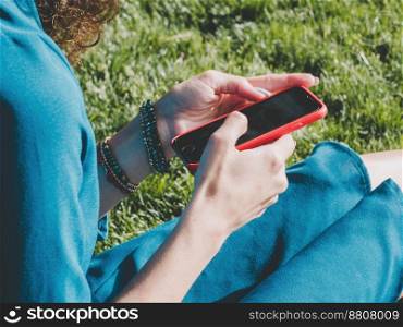 Hands of young woman using her mobile phone in green park. Girl with smartphone. Technology concept. High quality photo. Hands of young woman using her mobile phone in green park. Girl with smartphone. Technology concept.