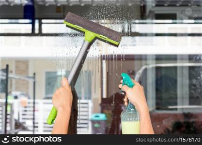 Hands of young woman wipe the glass with a glass cleaner-hobbies and leisure concepts.