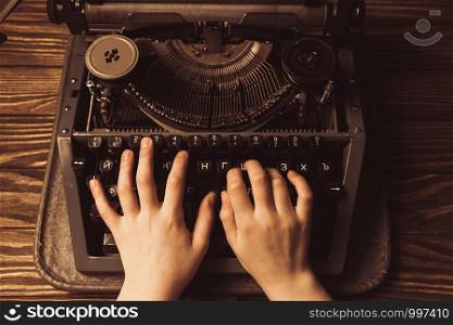 hands on a typewriter on a wooden background.. hands on a typewriter on a wooden background