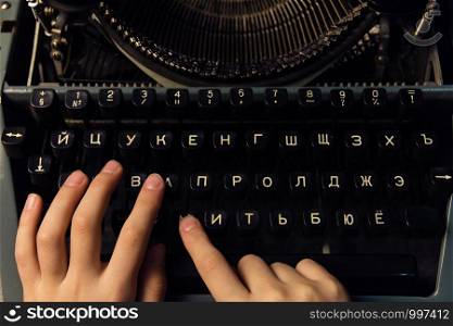 hands on a typewriter on a wooden background.. hands on a typewriter on a wooden background
