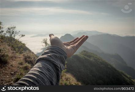Hands outstretched to receive natural light and mountain views, beautiful morning fog. hipster style.