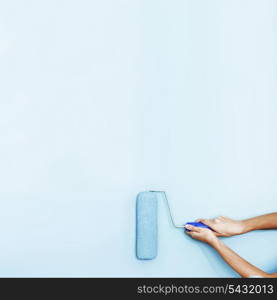 Hands painting the wall with a roller brush