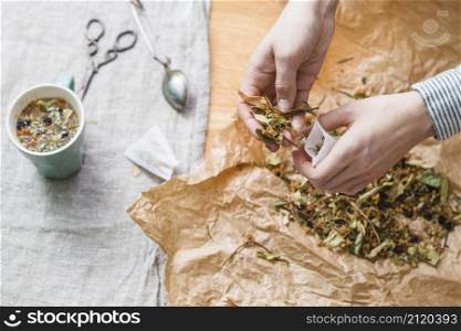 hands putting herbal mixture into tea bag