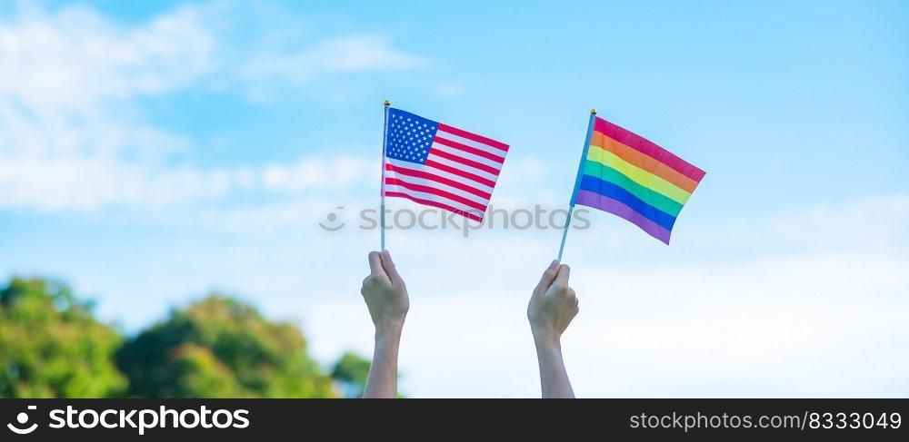hands showing LGBTQ Rainbow and America flag on nature background. Support Lesbian, Gay, Bisexual, Trans≥nder and Queer comμnity and Pride month concept