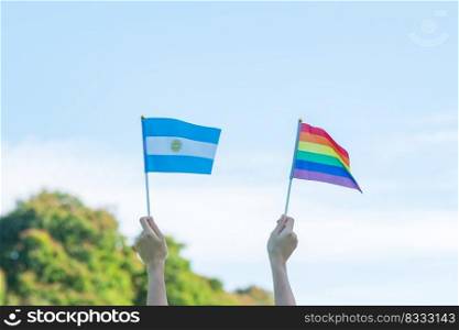 hands showing LGBTQ Rainbow and Argentina flag on nature background. Support Lesbian, Gay, Bisexual, Transgender and Queer community and Pride month concept