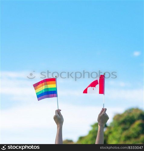 hands showing LGBTQ Rainbow and Canada flag on nature background. Support Lesbian, Gay, Bisexual, Transgender and Queer community and Pride month concept