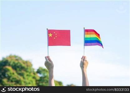 hands showing LGBTQ Rainbow and China flag on nature background. Support Lesbian, Gay, Bisexual, Transgender and Queer community and Pride month concept