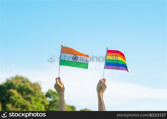 hands showing LGBTQ Rainbow and India flag on nature background. Support Lesbian, Gay, Bisexual, Transgender and Queer community and Pride month concept