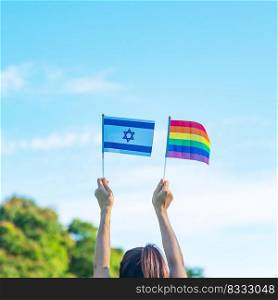 hands showing LGBTQ Rainbow and Isarael flag on nature background. Support Lesbian, Gay, Bisexual, Transgender and Queer community and Pride month concept