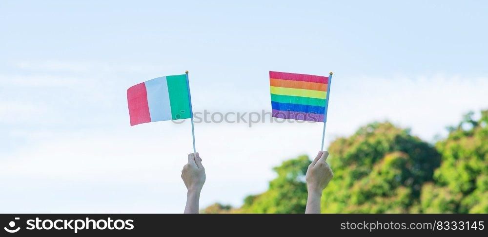 hands showing LGBTQ Rainbow and Italy flag on nature background. Support Lesbian, Gay, Bisexual, Transgender and Queer community and Pride month concept
