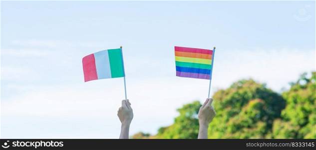 hands showing LGBTQ Rainbow and Italy flag on nature background. Support Lesbian, Gay, Bisexual, Transgender and Queer community and Pride month concept