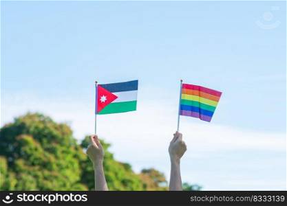 hands showing LGBTQ Rainbow and Jordan flag on nature background. Support Lesbian, Gay, Bisexual, Transgender and Queer community and Pride month concept