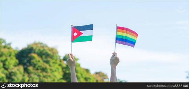 hands showing LGBTQ Rainbow and Jordan flag on nature background. Support Lesbian, Gay, Bisexual, Transgender and Queer community and Pride month concept