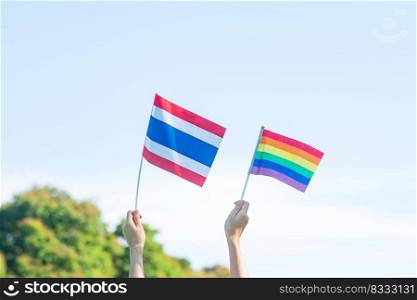 hands showing LGBTQ Rainbow and Thailand flag on nature background. Support Lesbian, Gay, Bisexual, Transgender and Queer community and Pride month concept