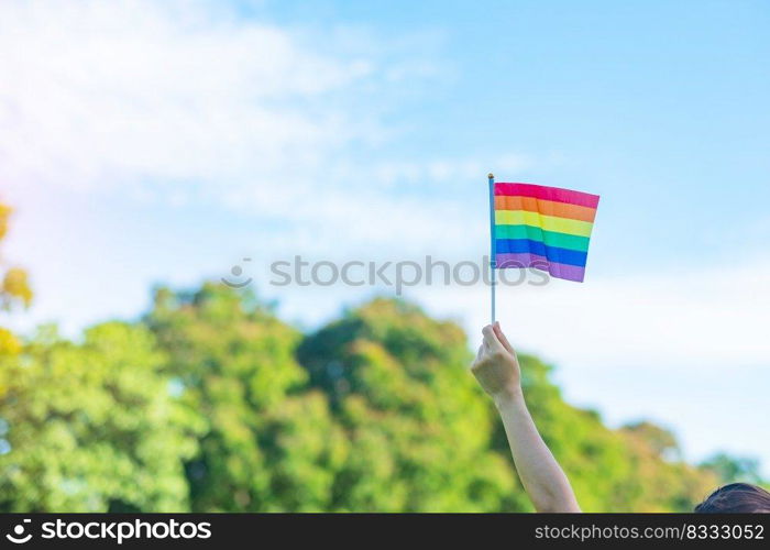 hands showing LGBTQ Rainbow flag on nature background. Support Lesbian, Gay, Bisexual, Transgender and Queer community and Pride month concept