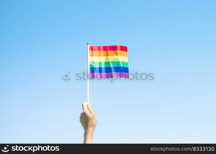 hands showing LGBTQ Rainbow flag on nature background. Support Lesbian, Gay, Bisexual, Transgender and Queer community and Pride month concept