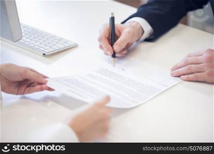 Hands signing contract. Human hands working with documents, signing contract at the desk closeup