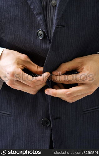 Hands un-buttoning a gray pinstriped business suit closeup