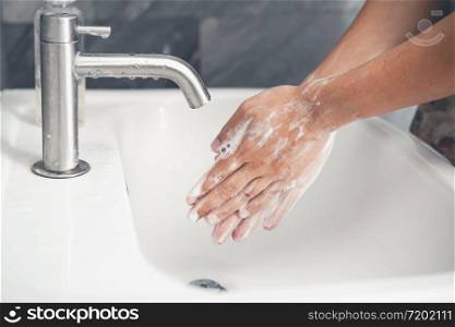 Hands washing for prevention of novel Coronavirus Disease 2019 or COVID-19 . People wash hands at bathroom sink to clean the virus infection.