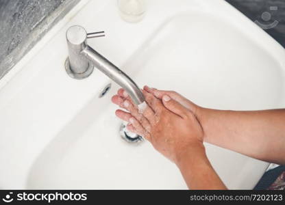 Hands washing for prevention of novel Coronavirus Disease 2019 or COVID-19 . People wash hands at bathroom sink to clean the virus infection.