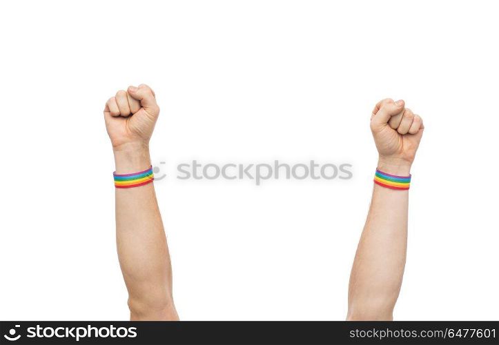 hands with gay pride rainbow wristbands shows fist. lgbt, same-sex relationships and homosexual concept - close up of male hands wearing gay pride awareness wristbands showing fist