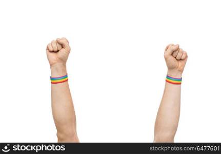 hands with gay pride rainbow wristbands shows fist. lgbt, same-sex relationships and homosexual concept - close up of male hands wearing gay pride awareness wristbands showing fist