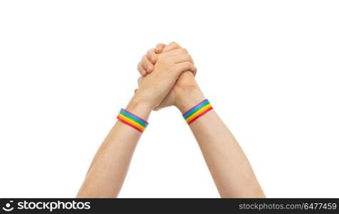 hands with gay pride wristbands in winning gesture. lgbt, same-sex relationships and homosexual concept - close up of male hands wearing gay pride awareness wristbands making winning gesture