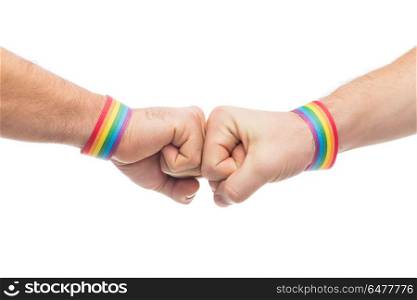 hands with gay pride wristbands make fist bump. lgbt, same-sex love and homosexual relationships concept - close up of male couple hands with gay pride rainbow awareness wristbands making fist bump gesture