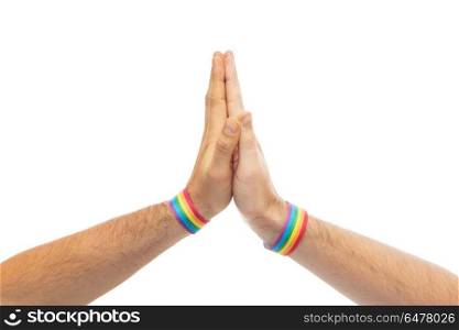 hands with gay pride wristbands make high five. lgbt, same-sex love and homosexual relationships concept - close up of male couple hands with gay pride rainbow awareness wristbands making high five gesture