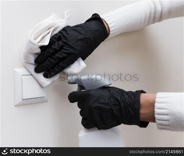 hands with gloves disinfecting light switch